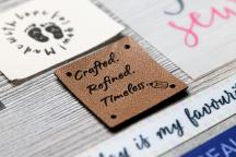 Brunt konstlädermärke med lasergraveringen 'Crafted. Refined. Timeless.' - Artikelnummer 3007